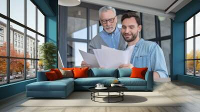 Caring loving adult son helping his old senior elderly father paying bills, counting money, doing paperwork at home together. Aid to elderly generation. Happy father`s day! Wall mural